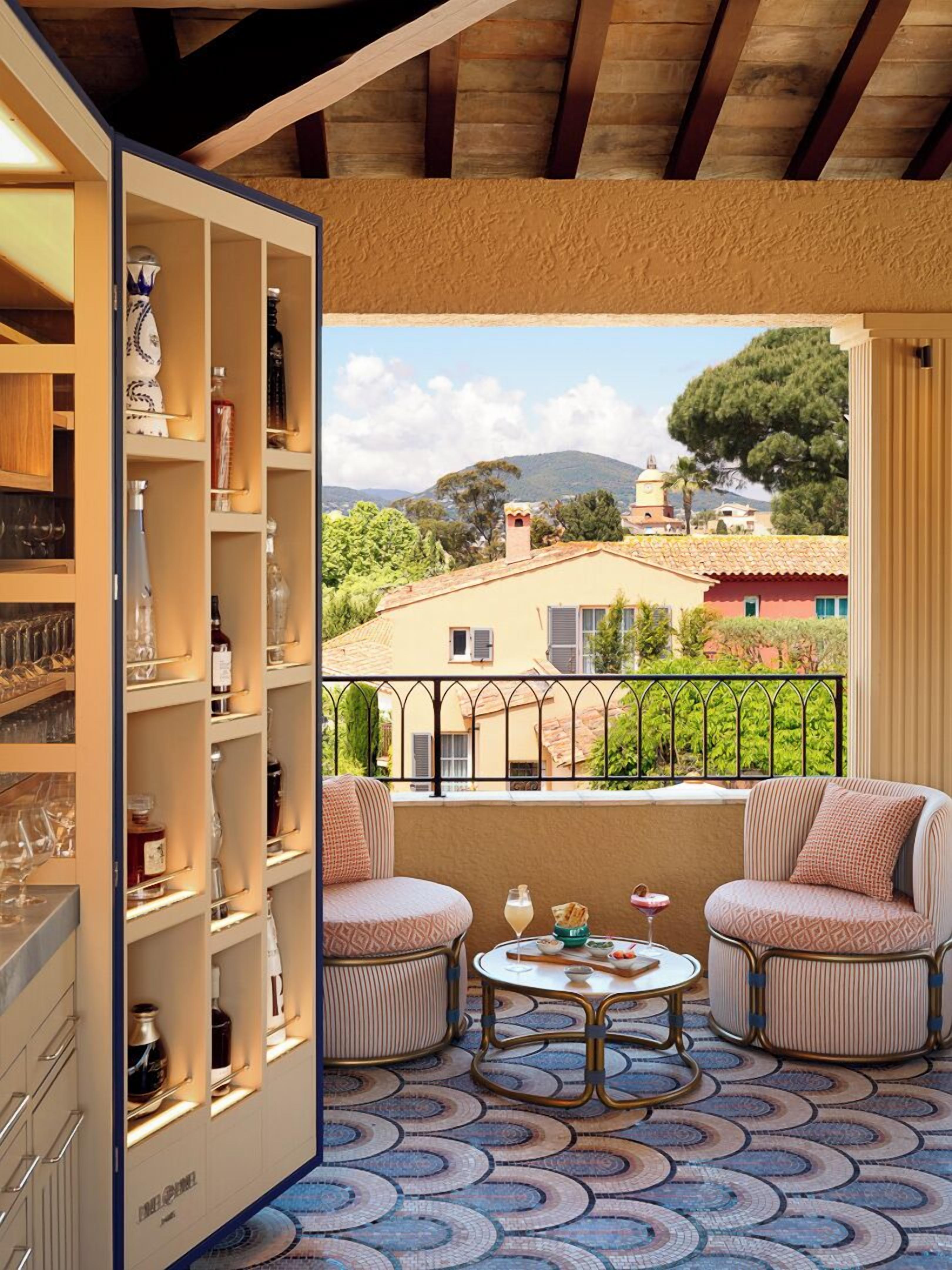 Un balcon avec deux fauteuils confortables, une petite table ronde et un porte-bouteilles.