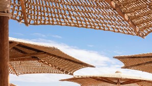 Een strandlounge met ligbedden en parasols.