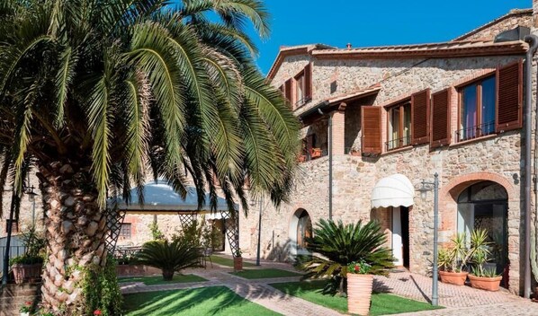 A stone building with arched windows and a covered patio area. - B&B Suvereto (Suvereto)