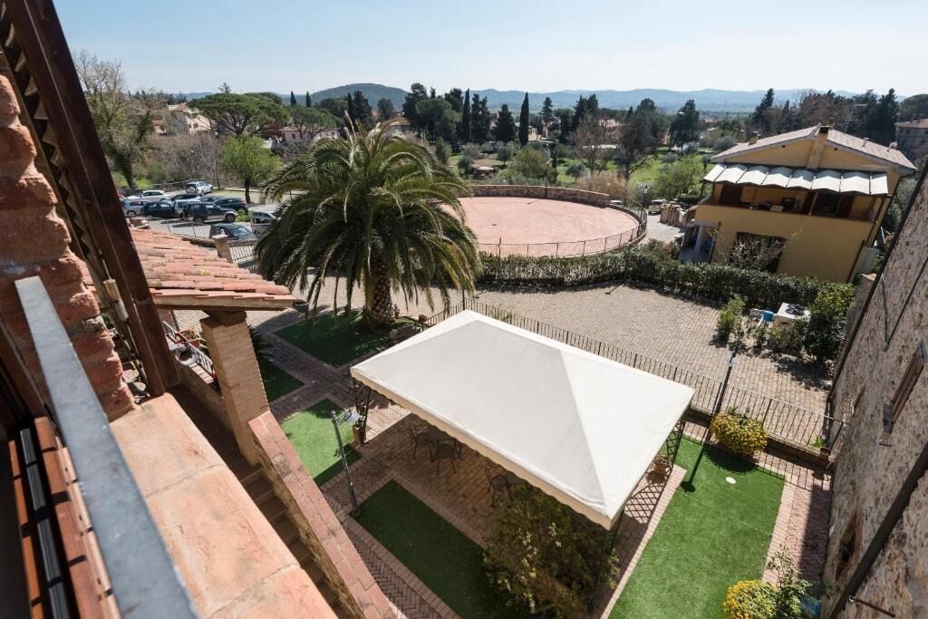 A courtyard with a white canopy, a palm tree, and a building with a tiled roof.