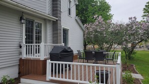 Een huis met een overdekte patio, een barbecue en een witte balustrade.