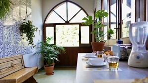 A kitchen with a wooden bench, potted plants, a blender, and a window with a view of trees. - Solemar Sicilia - Villa Caterina (Cefalù)