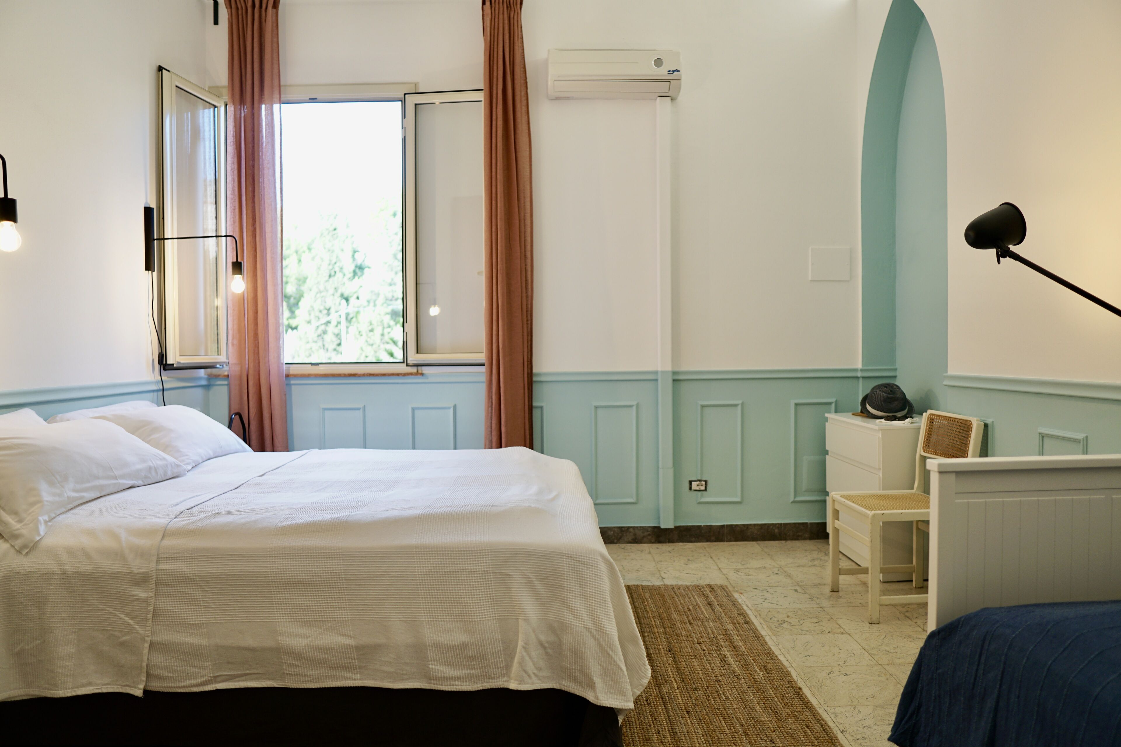 A bedroom with a bed, a dresser, a chair, and a window with curtains.