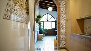 A kitchen with wooden cabinets, a tiled backsplash, and a hanging plant. - Solemar Sicilia - Villa Caterina (Cefalù)