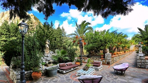 An outdoor patio area with stone flooring, lounge chairs, and potted plants. - Solemar Sicilia - Villa Caterina (Cefalù)