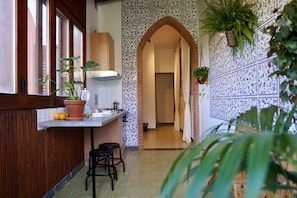 Uma cozinha com bancada de madeira, banquetas e plantas em vasos.