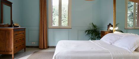 Un dormitorio con cama, cómoda, espejo, ventana y cortinas.