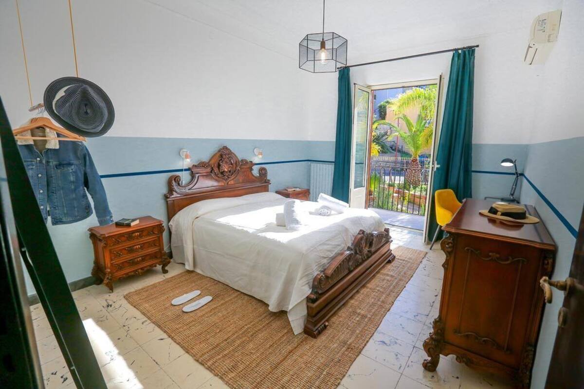 A bedroom with a bed, wooden dresser, and a fan.