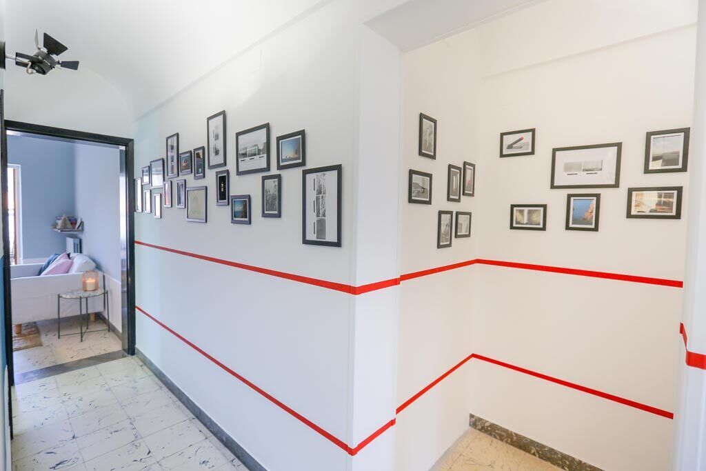 A hallway with framed pictures on the walls and red lines marking the floor.