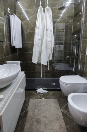 A modern bathroom with a large sink, toilet, and bidet. There are two white towels hanging on hooks and a pair of slippers on the floor. - Arena di Verona Rensi Italianflat (Verona)