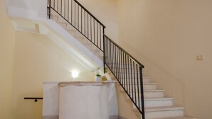 A staircase with a handrail, a light fixture on the wall, and a small plant on the landing. - Arena di Verona Rensi Italianflat (Verona)