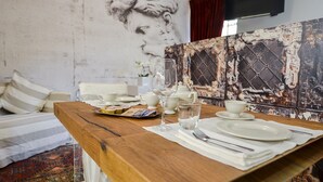 A dining table set with white plates, cups, and cutlery, with a vintage-style wall mural in the background. - Arena di Verona Rensi Italianflat (Verona)