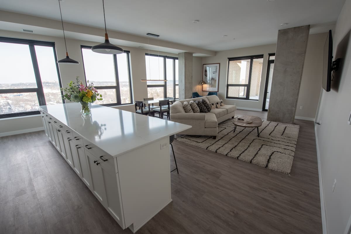 A modern kitchen with a white island, large windows, and a city view.