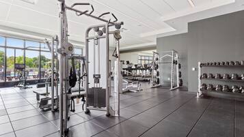 Un gimnasio moderno con diverso equipo de ejercicio, amplias ventanas y un diseño espacioso y limpio.