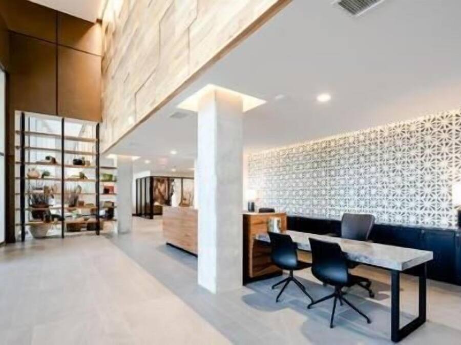 A spacious, modern office with a high ceiling, a reception desk, and a seating area with chairs.