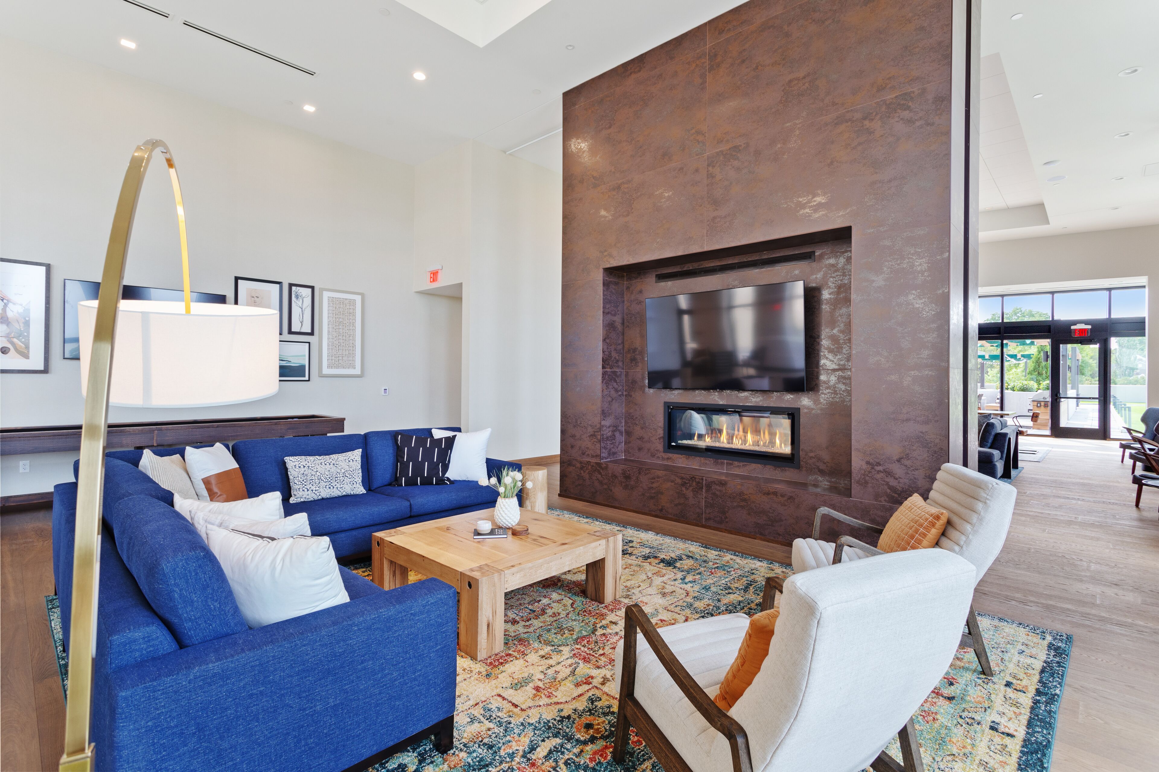 A modern living room with a blue sofa, white armchairs, a wooden coffee table, and a fireplace.