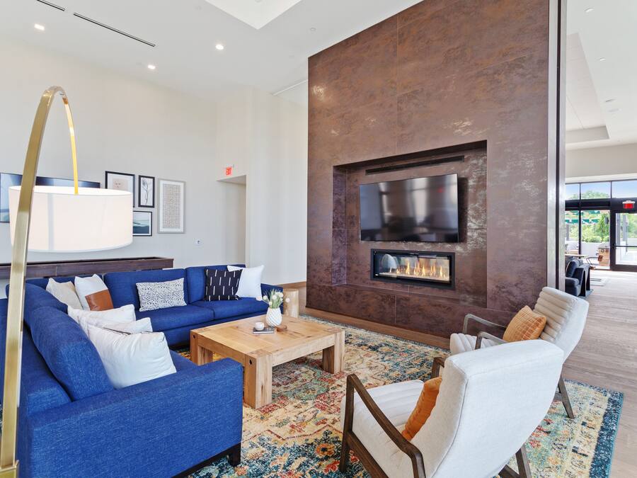 A modern living room with a blue sofa, white armchairs, a wooden coffee table, and a fireplace.