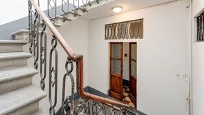 Eine Treppe mit aufwendigen Metallgeländern und einem hölzernen Handlauf, die zu einem Raum mit Schachbrettboden und einer Holztür führt.