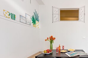 A dining area with a table set for two, featuring a bowl of fruit, a vase of flowers, and a plate of food. - Acquamarina - Sweet Dreams in Florence (Firenze)