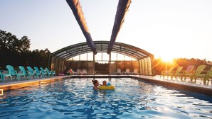 A swimming pool with a glass roof, surrounded by lounge chairs. - Resort Stara Wieś (Patnów)