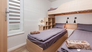A bedroom with a bunk bed, a window with blinds, a teddy bear on a shelf, and a lamp on the wall. - Resort Stara Wieś (Patnów)