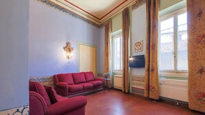 A room with a red sofa, a small table, and a window with curtains.