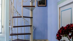 A spiral staircase with metal railings and wooden steps, a blue wall with a framed picture, and a door with a blue frame.