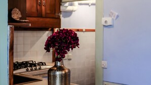 A kitchen with a stainless steel sink, a stove, and a vase with purple flowers on the counter.