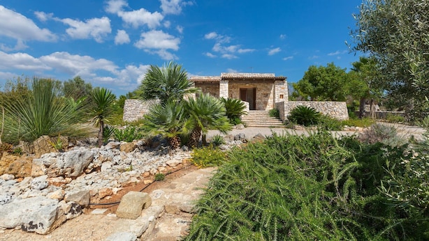 A stone building with a tiled roof, surrounded by greenery and a stone pathway leading to the entrance. - Villa Mila by Perle di Puglia (Torre Vado)