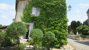 Une maison avec un toit en tuiles, des murs couverts de lierre, une fenêtre visible et un lampadaire.