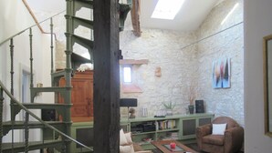 Une pièce avec un escalier, un mur en pierre, un canapé, une table basse et une bibliothèque.