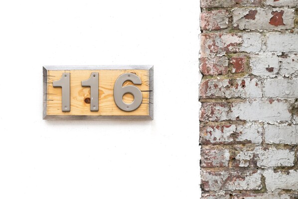 A wooden house number sign with the number 116. - Luxury apartment with a private rooftop deck located in the heart of downtown JC (Johnson City)