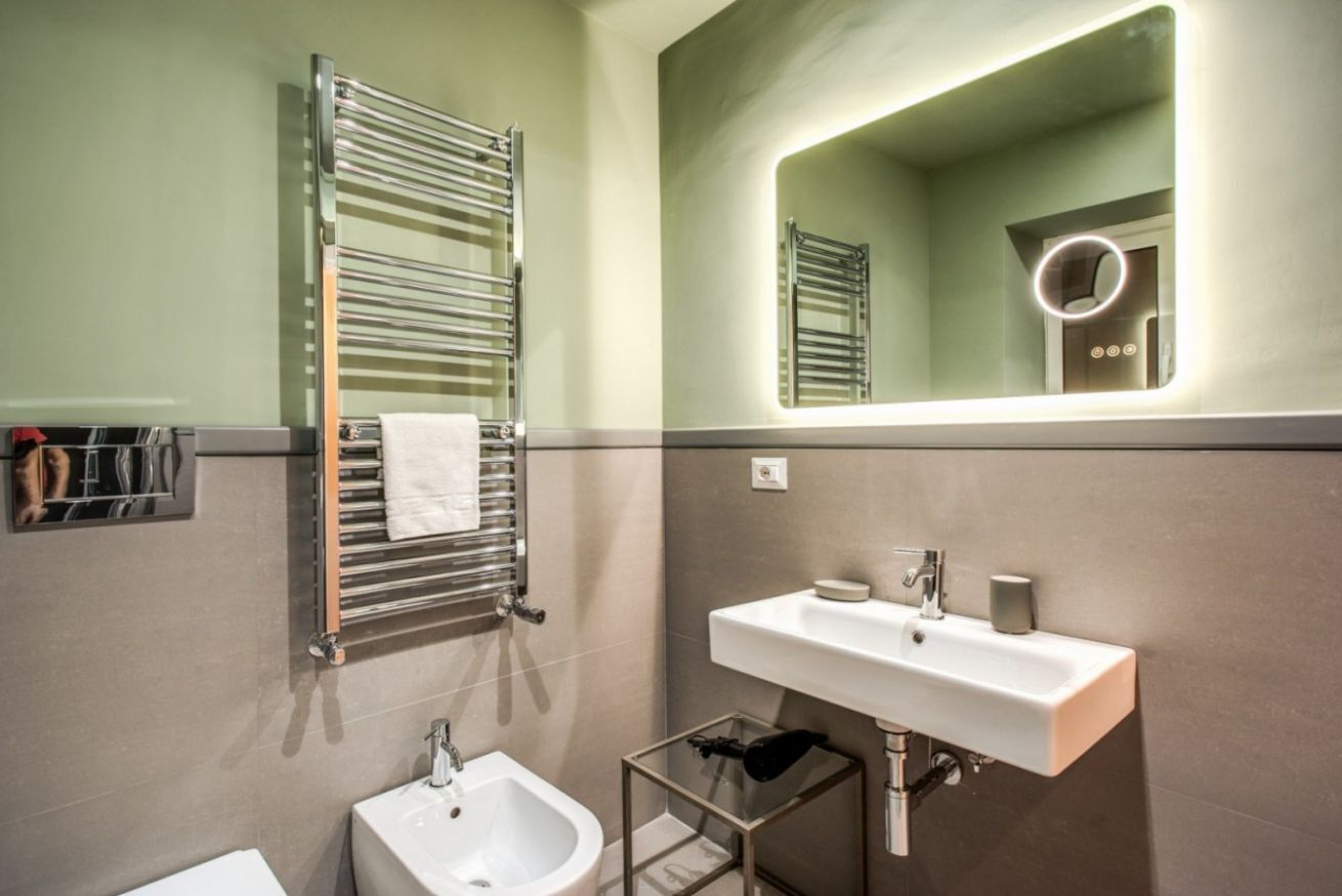Une salle de bain moderne avec un grand miroir, un porte-serviettes, un lavabo et un bidet.