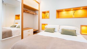 Een moderne slaapkamer met een groot bed, een houten garderobe en inbouwkasten met decoratieve objecten.