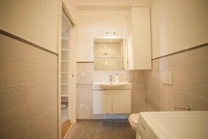Ein kleines Badezimmer mit Waschbecken, Spiegel und Toilette.