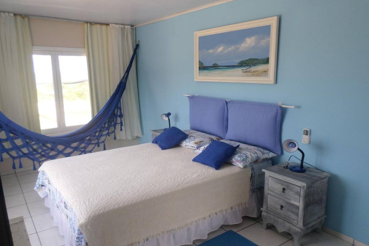 Un dormitorio con una cama, una mesita de noche, una hamaca y un cuadro en la pared.