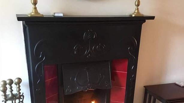 Una chimenea con marco de ladrillo rojo y repisa negra.