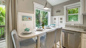Una cocina con una mesa de comedor preparada para cuatro personas, un lavavajillas y una ventana con vistas a la vegetación.