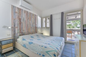 Une chambre à coucher avec un lit, une tête de lit en bois, une table de chevet, un téléviseur et une vue sur l’extérieur.