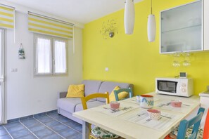 A compact living space with a kitchenette, a dining area, and a sofa.