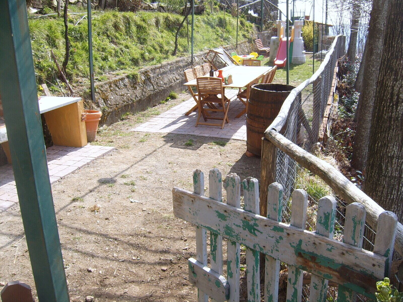 A patio area with a table and chairs, surrounded by a wooden fence and a stone wall.