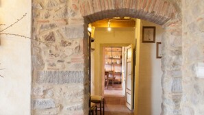 A stone archway leading to a hallway with a tiled floor and a wooden bench. - Stone house with 4 double bedrooms and kitchen with fireplace (Boveglio)