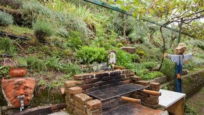 A rustic outdoor grill area with a brick structure, a metal grill, and a rustic water feature. - Stone house with 4 double bedrooms and kitchen with fireplace (Boveglio)