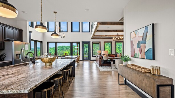 Una cocina amplia con una isla grande, taburetes de bar y vistas al exterior a través de grandes ventanales.