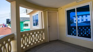 A corner room with a balcony, a door, and a window with a decorative screen. - Brannic Lodge - Hostel (Accra)