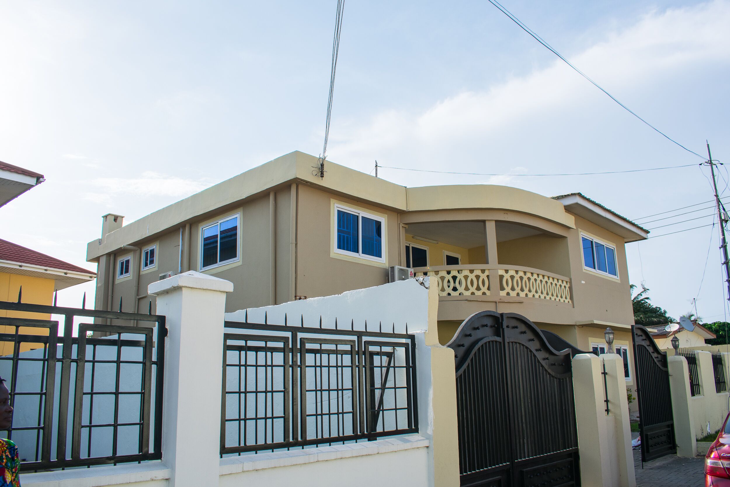 Une maison à deux étages avec une entrée fermée par un portail, un balcon et une antenne parabolique.