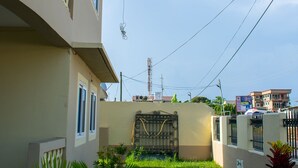 A residential building with a paved driveway, a small lawn, and a gated entrance. - Brannic Lodge - Hostel (Accra)