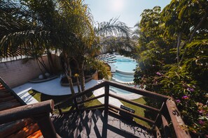 Uma área de piscina com deck de madeira e vegetação exuberante ao redor.