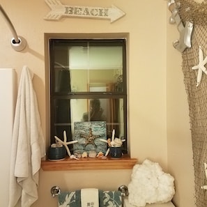 Enjoy a beachside view from the bathroom window, complete with a framed beach scene and decorative seashells.