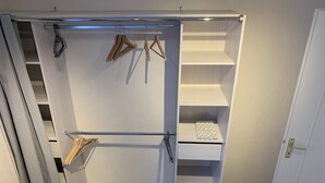 Un dressing avec des étagères ouvertes, une tringle et une porte coulissante.